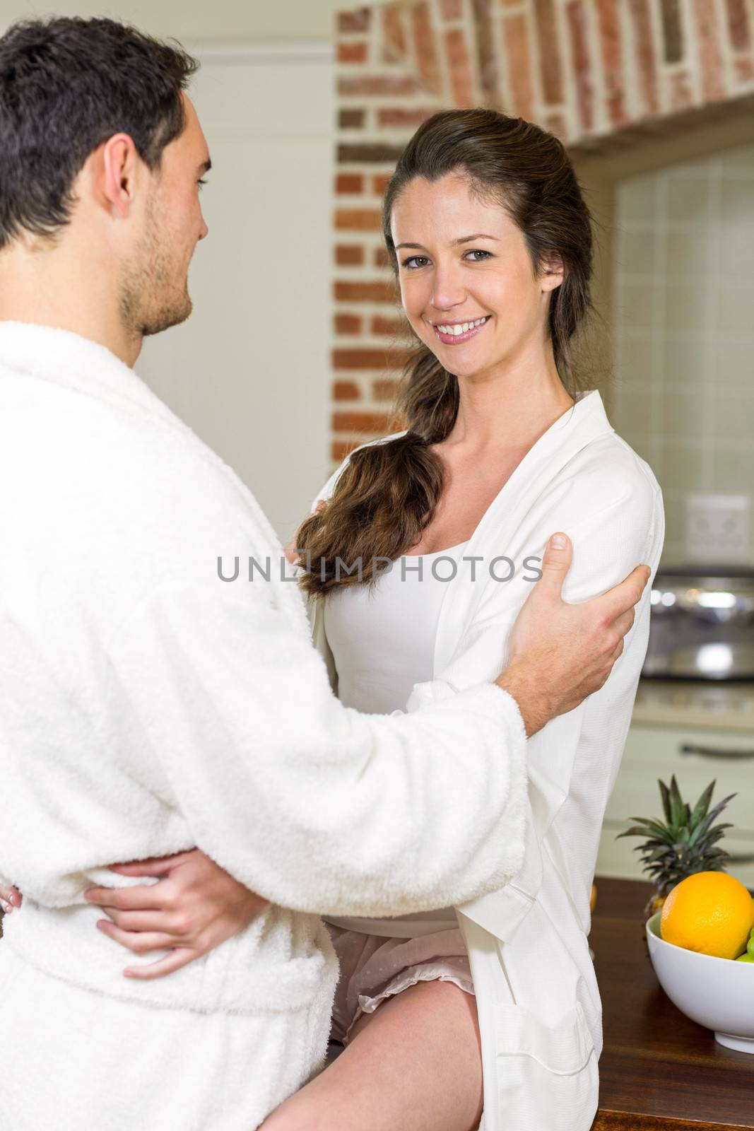 Young couple in bathrobe cuddling each other by Wavebreakmedia