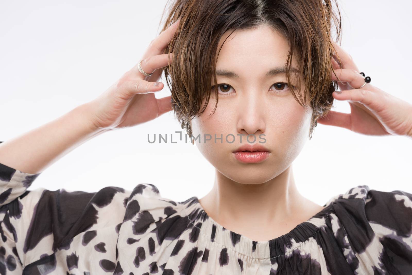 A high key headshot of a young and beautiful Japanese woman in a strong and confident pose on a white background.