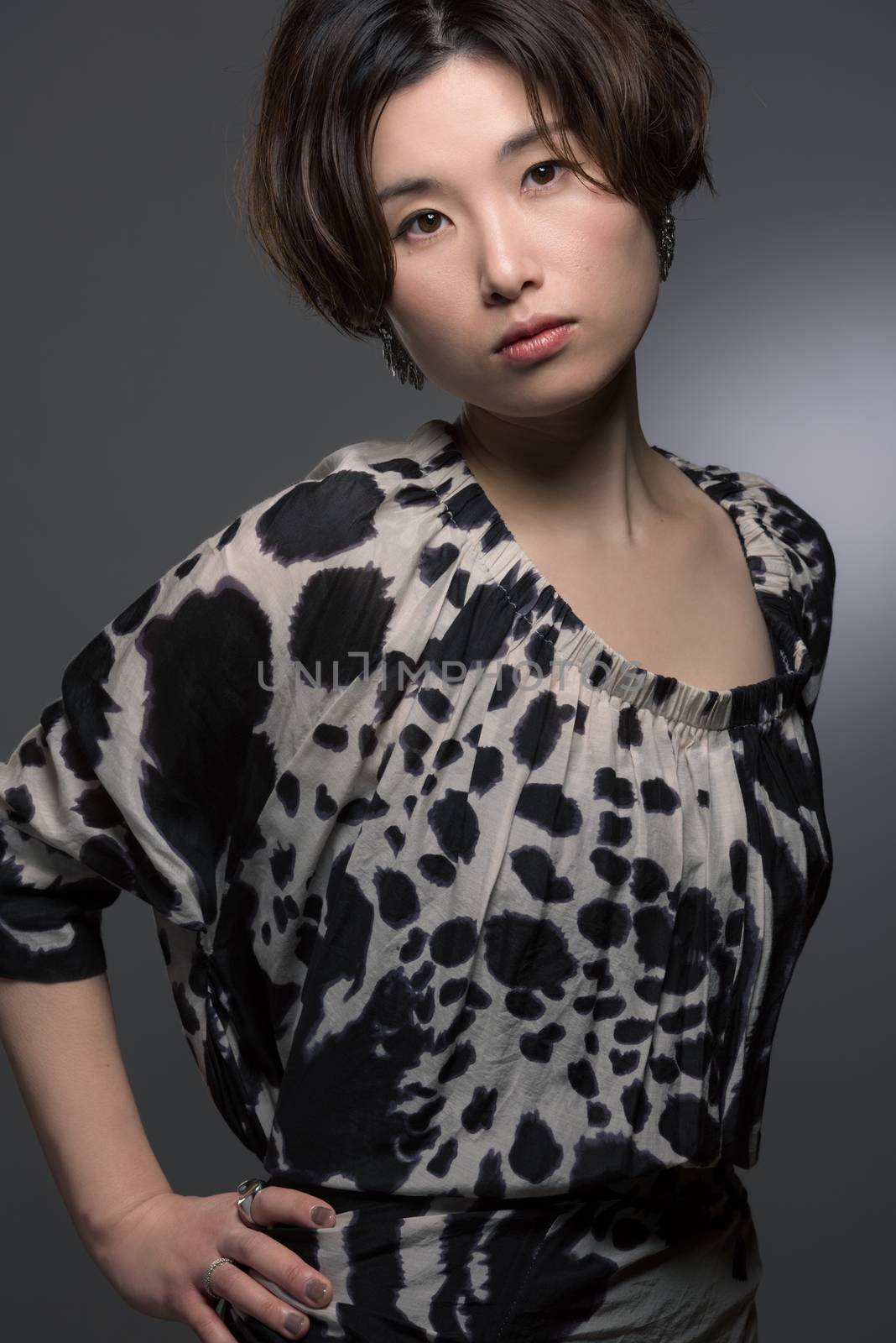A portrait of a young and beautiful Japanese woman posed confidently shot on a dark background.