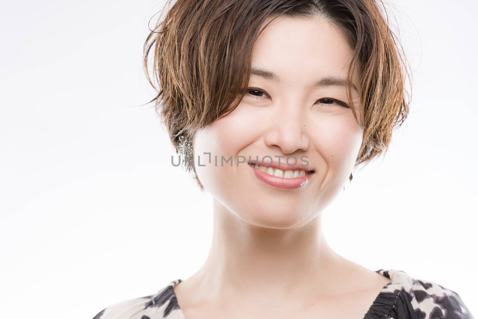 A high key headshot of a smiling, beautiful and young Japanese woman on a white background.