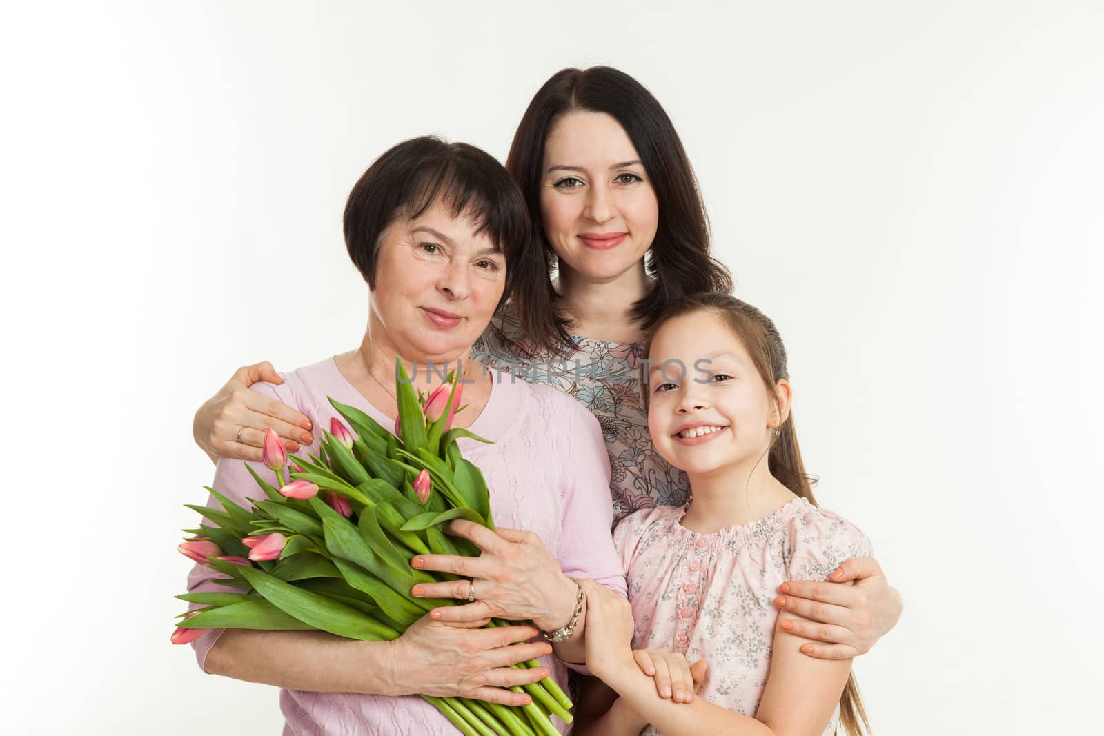 the mature woman, the young woman and the girl stand nearby and hold a bouquet of tulips