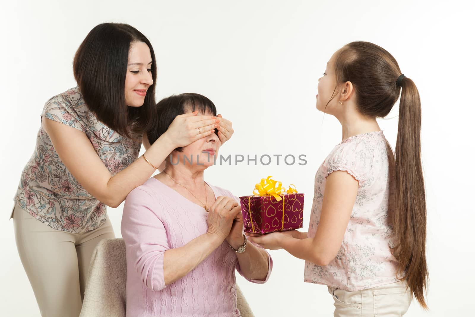the daughter and the granddaughter give a gift to the grandmother