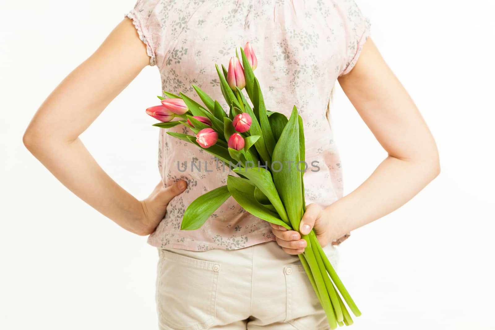 the girl holds a bouquet of tulips behind the back