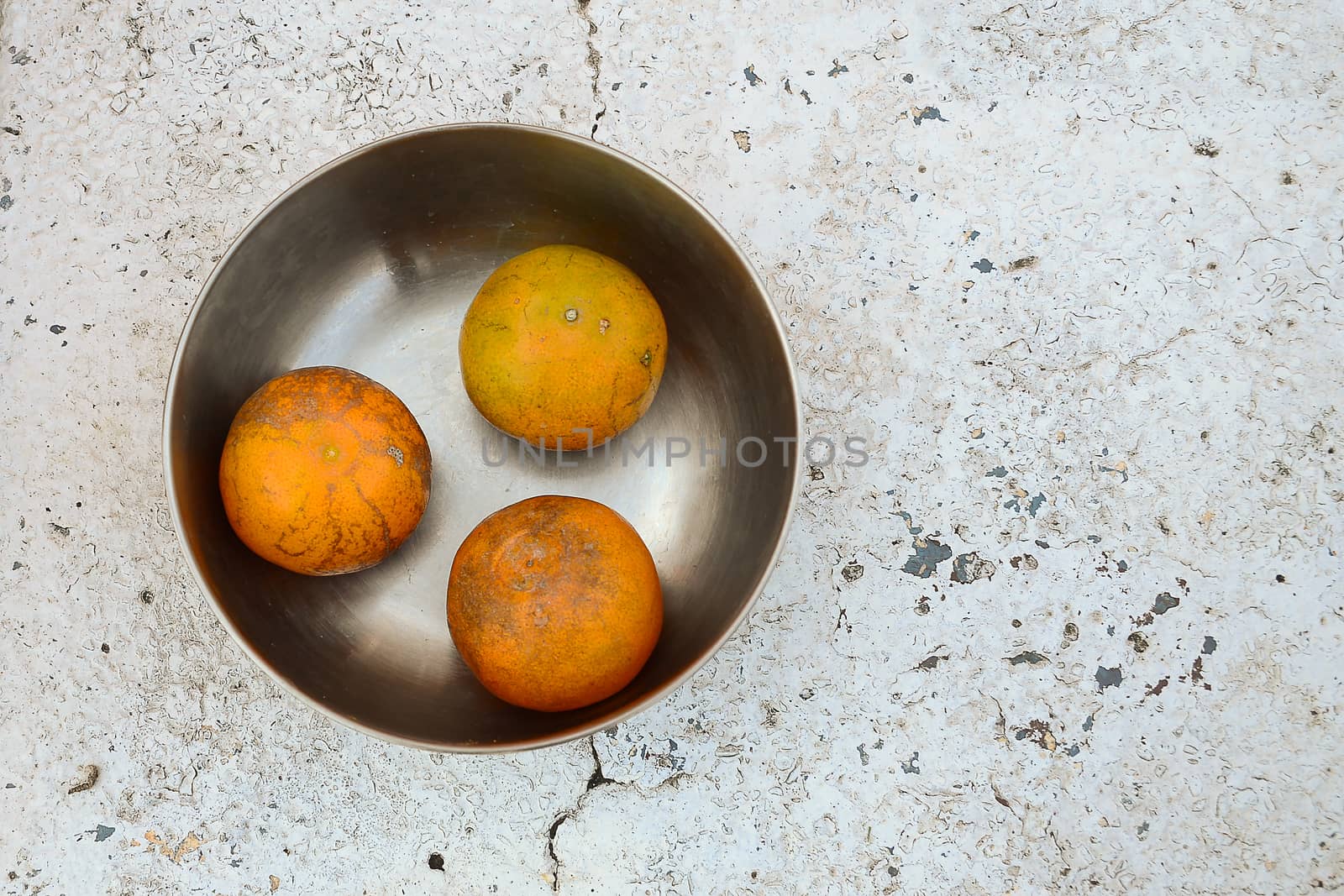 tree oranges in stainless steel bowl on white stone table