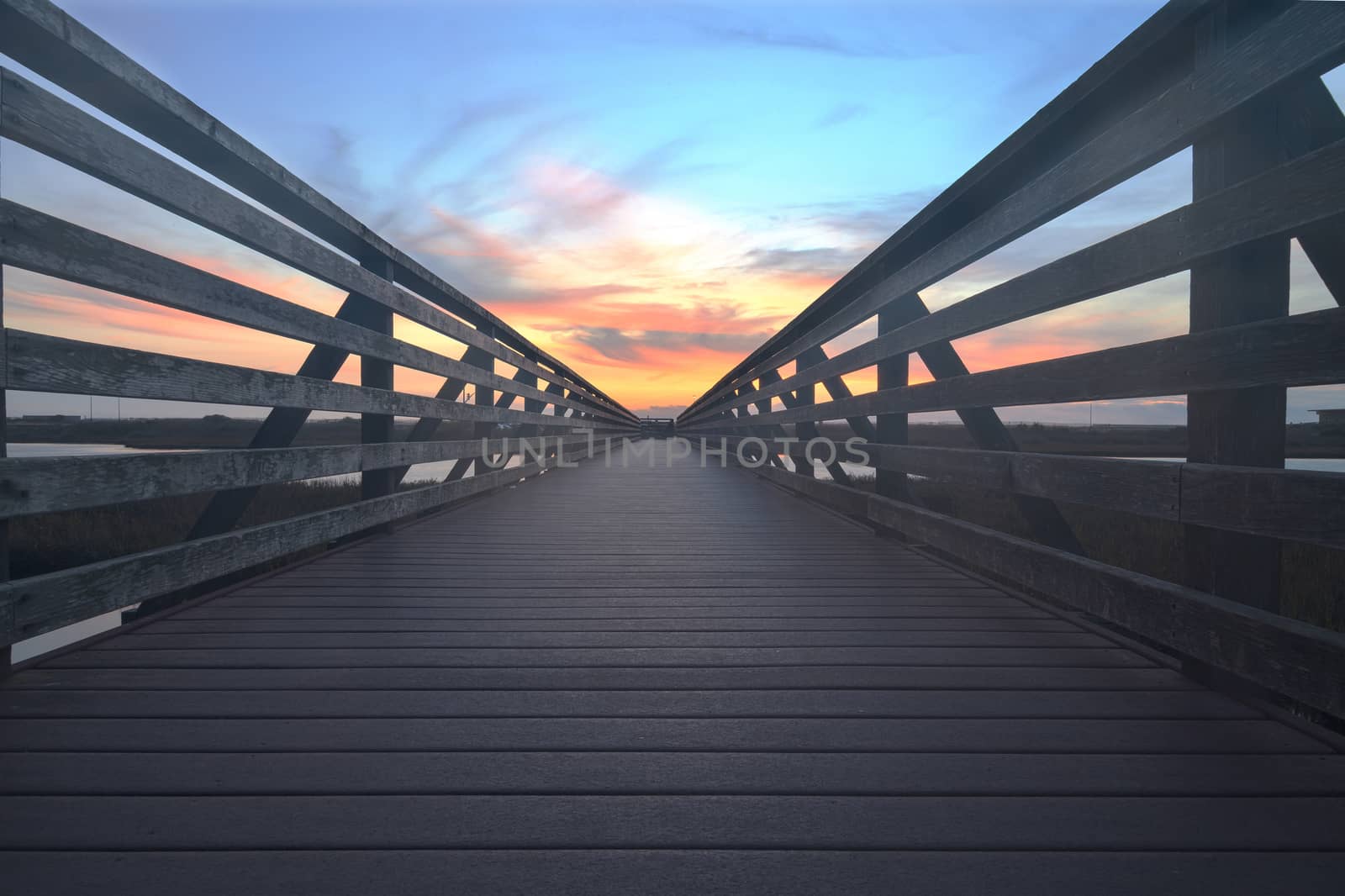 Wooden Boardwalk at sunset, to journey through Bolsa Chica Wetlands preserve in Huntington Beach, California, United States