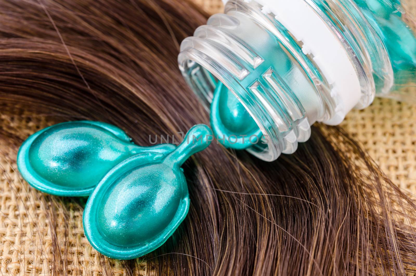 Hair vitamin serum capsule with damaged hair on sack background.