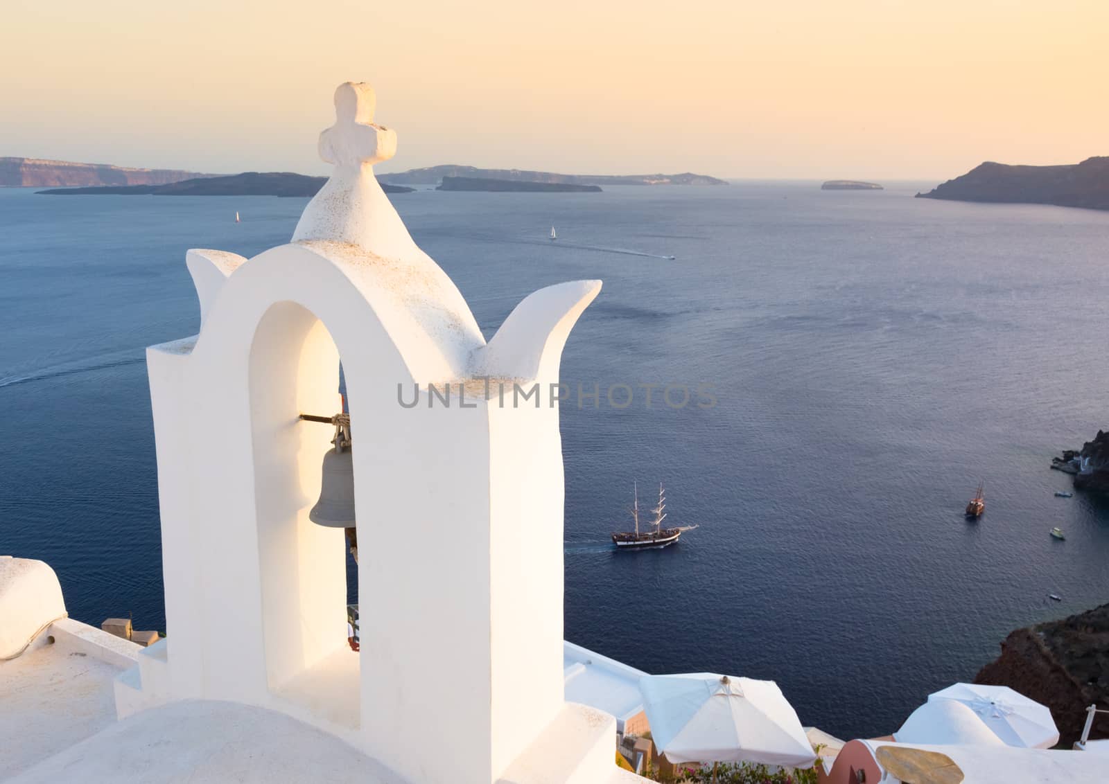World famous traditional whitewashed chuche of Oia village on Santorini island, Greece. Sunset light.