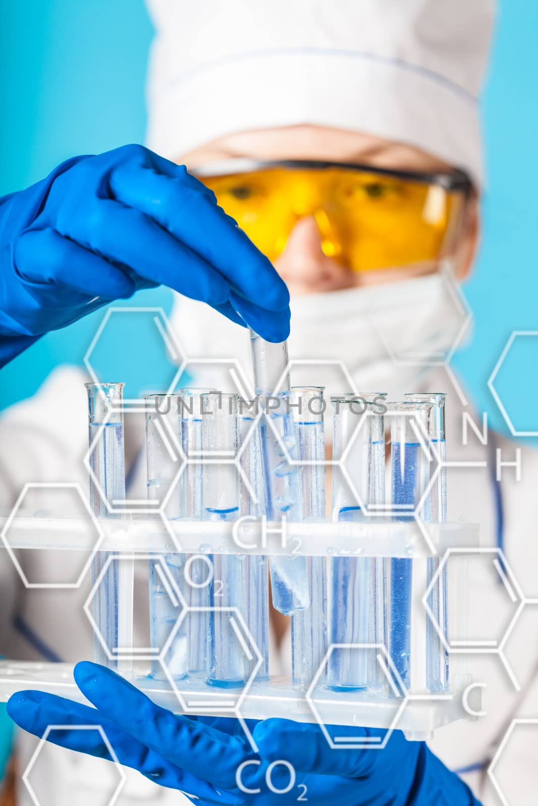 Woman chemist examines test tube on a blue background