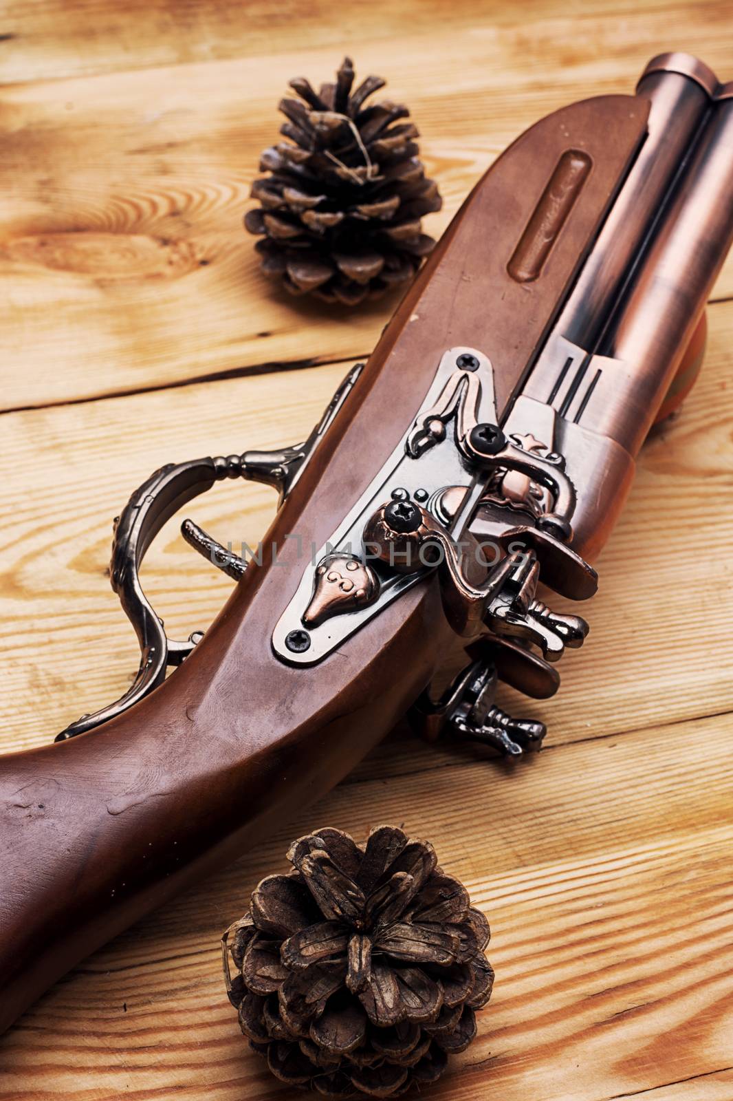 Old hunting musket on a light wooden background with forest cones