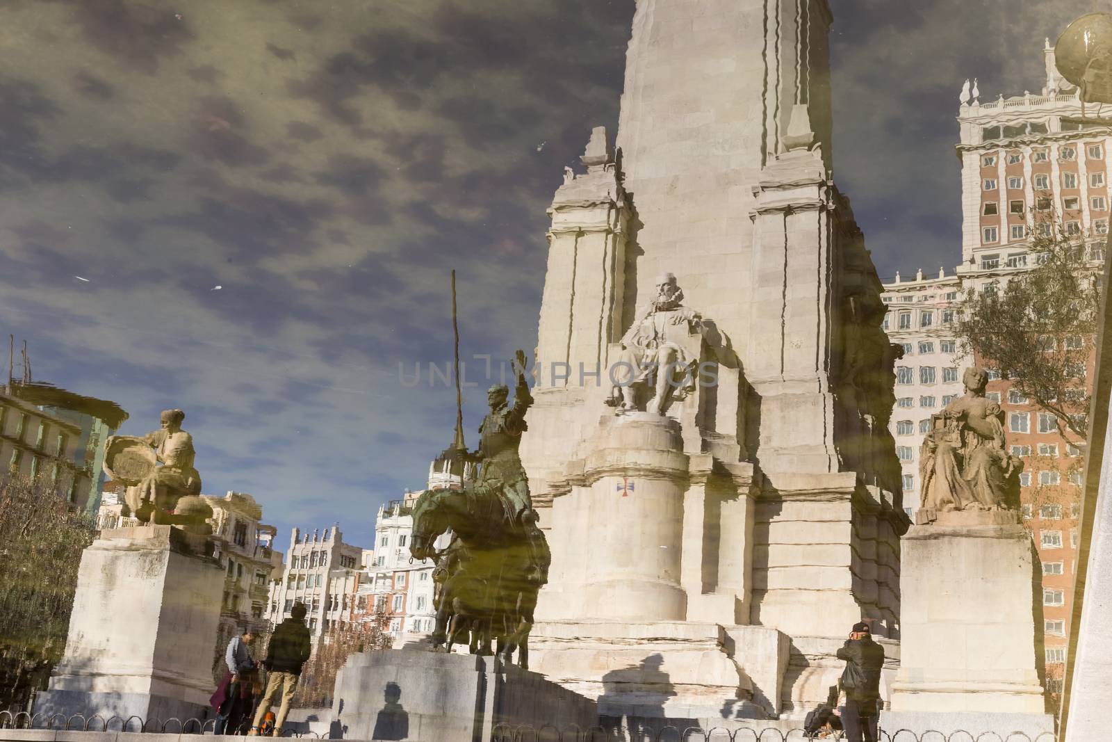 Reflection in water of stone statue of Miguel de Cervantes and bronze sculptures of Don Quixote and Sancho Panza on the Square of Spain (Plaza de Espana) in Madrid.