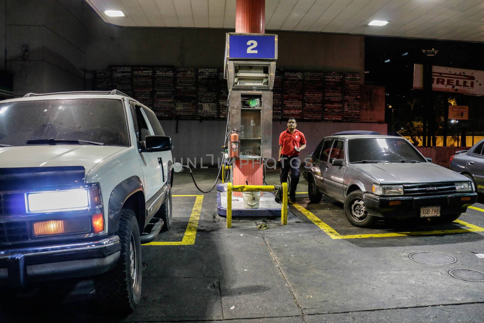 VENEZUELA, Caracas: An employee of a gas station fills cars in Caracas, on February 17, 2016. Venezuela's President Nicolas Maduro said Wednesday he would raise the price of gasoline for the first time in 20 years, as he faces growing pressure to ease an economic crisis. Maduro said in a televised address he would raise the pump price of premium gasoline from its current super-low level of $0.01 to the equivalent of $0.95 at the fixed official exchange rate, in a country where citizens are struggling with soaring inflation.