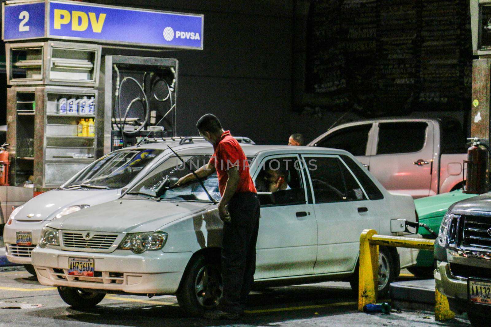 VENEZUELA, Caracas: An employee of a gas station fills and washes a car in Caracas, on February 17, 2016. Venezuela's President Nicolas Maduro said Wednesday he would raise the price of gasoline for the first time in 20 years, as he faces growing pressure to ease an economic crisis. Maduro said in a televised address he would raise the pump price of premium gasoline from its current super-low level of $0.01 to the equivalent of $0.95 at the fixed official exchange rate, in a country where citizens are struggling with soaring inflation.
