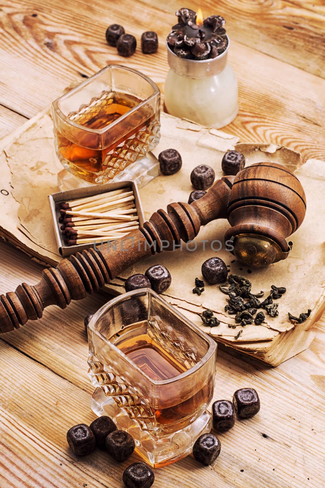 Smoking pipe in a retro style,dark chocolate and glasses of whiskey on wooden background