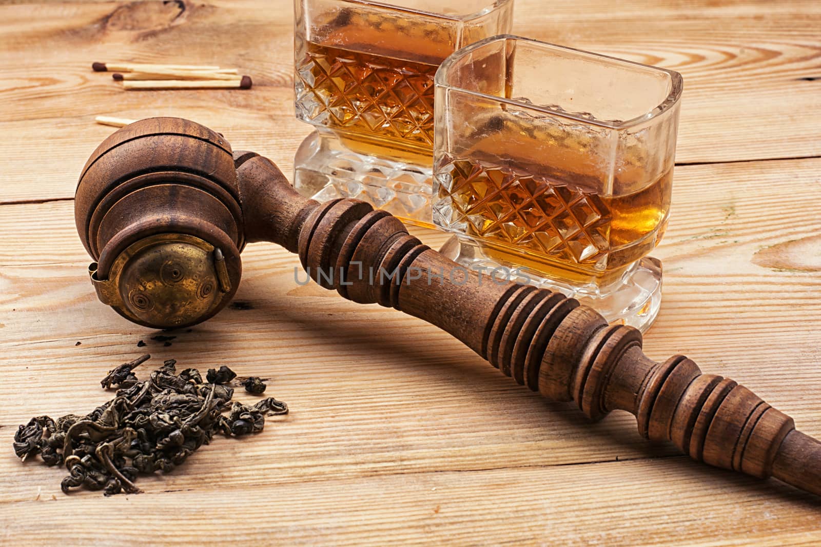 Smoking pipe in a retro style,dark chocolate and glasses of whiskey on wooden background