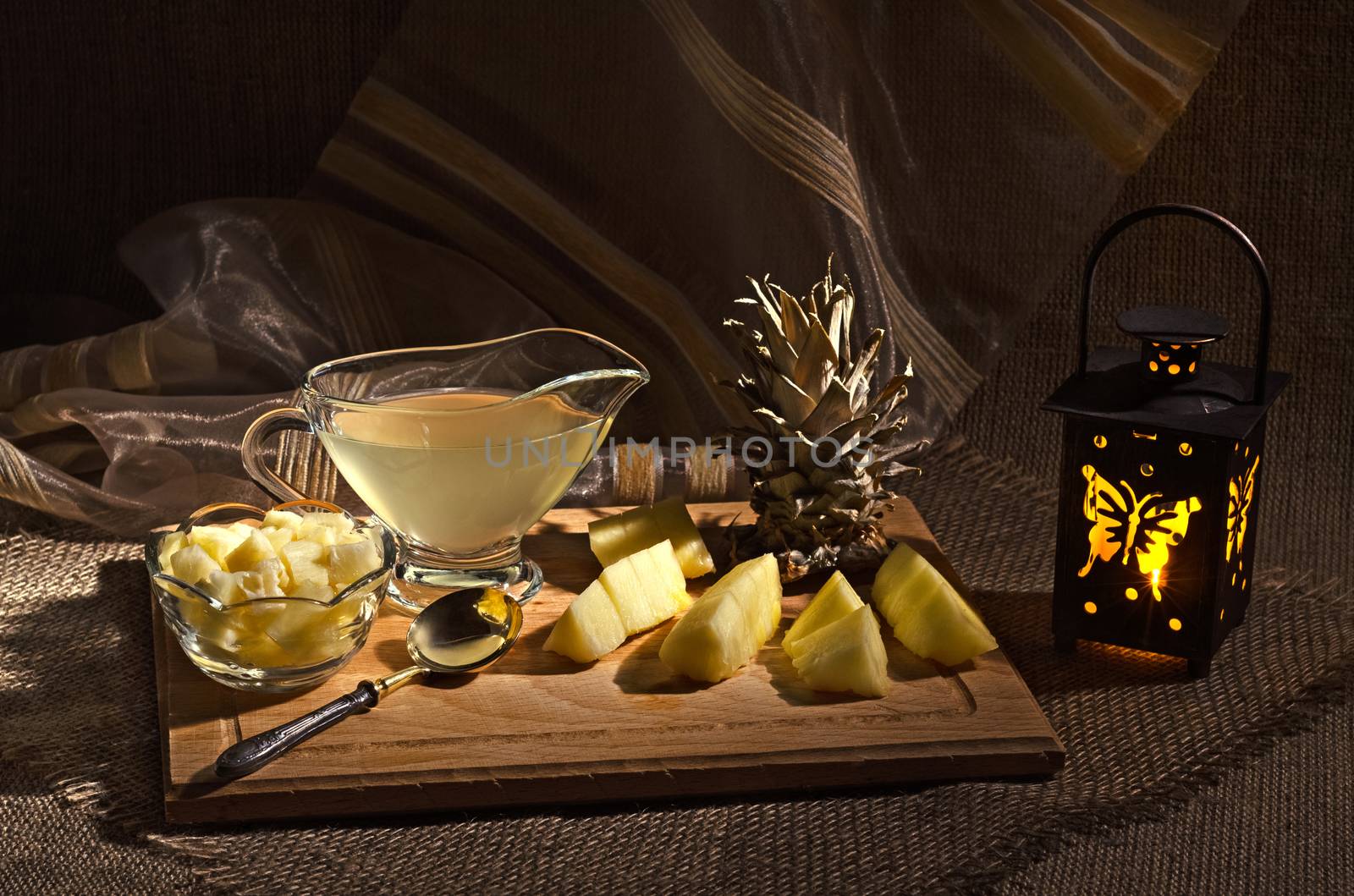 Juice and sliced pineapple, and a lit flashlight on a table.