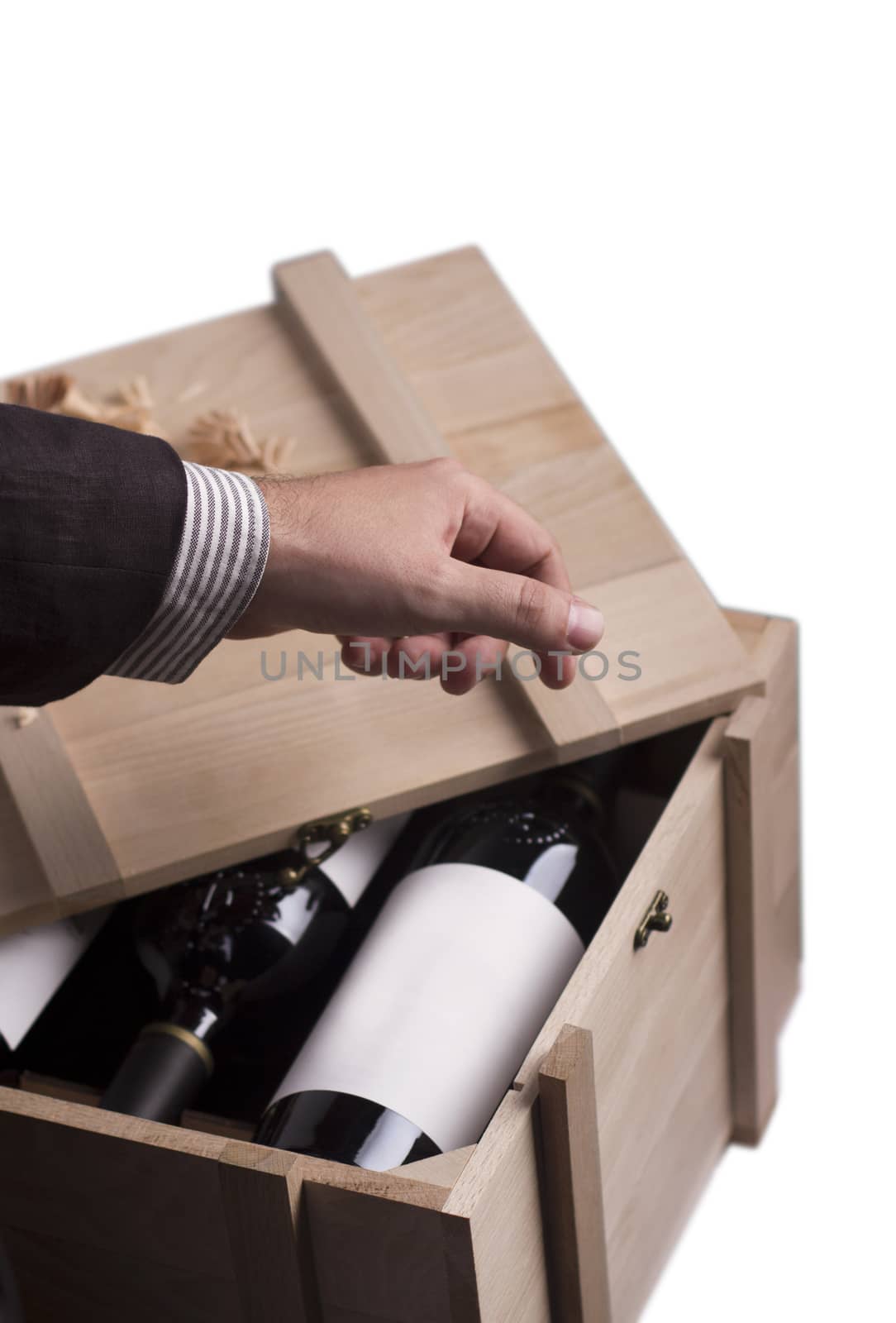 A hand choosing a bottle of wine from a wooden crate