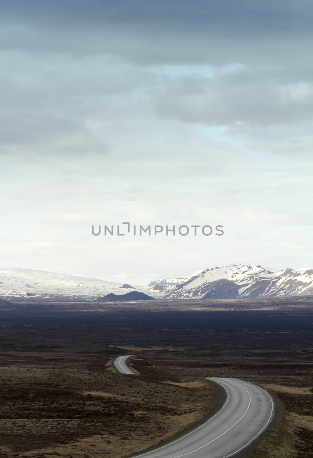 Vertical photo of a winding asphalt road going into the mountains in Thingvellir national park in Iceland
