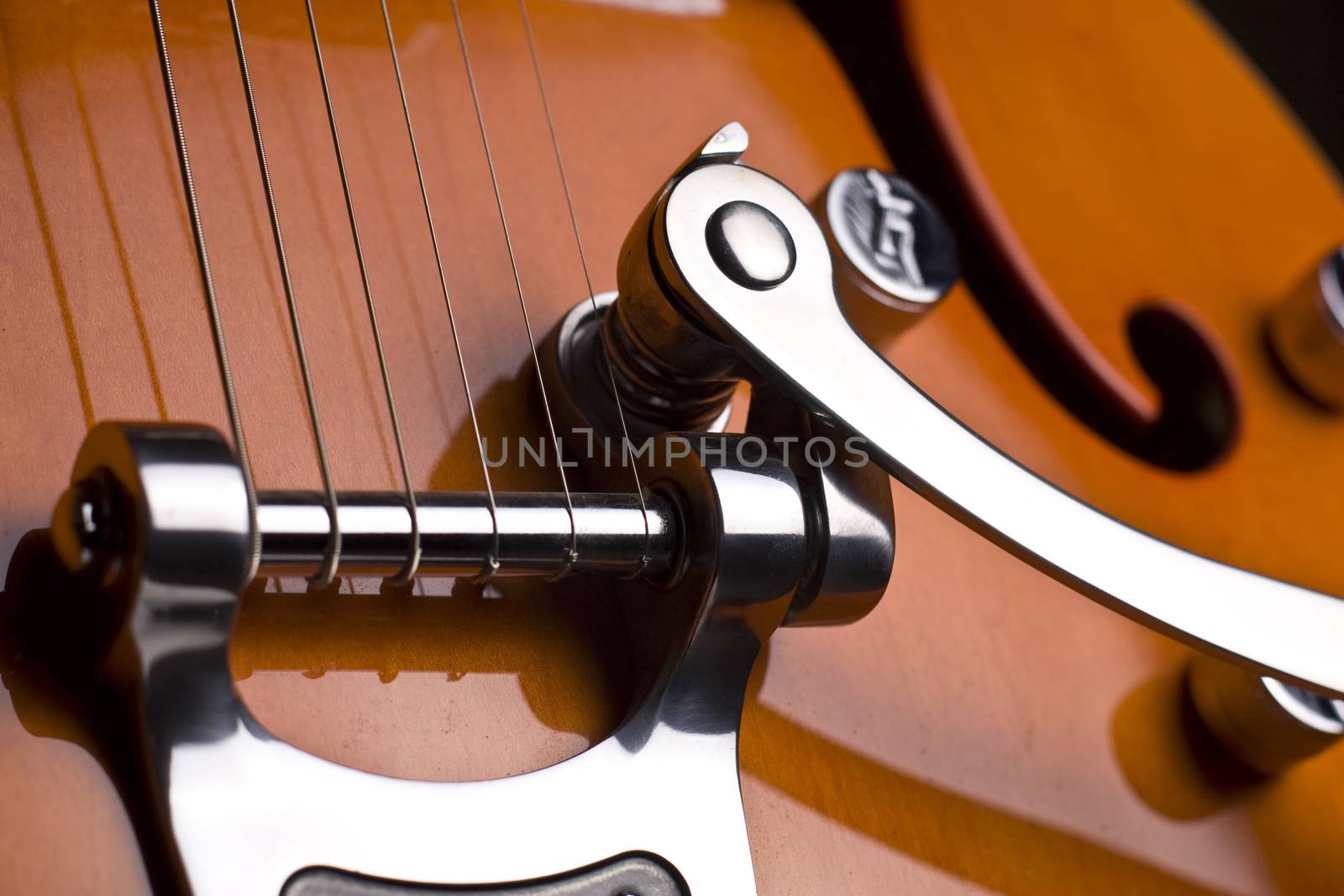 Vertical close up of the chords of an orange electrical guitar on black background