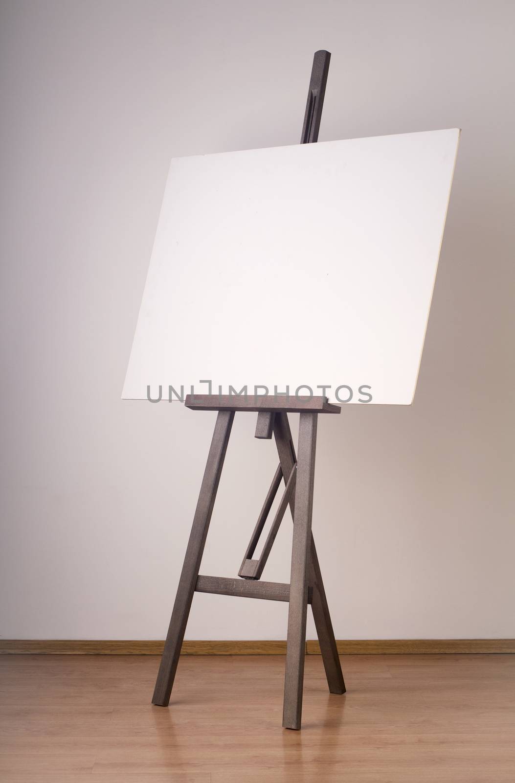 Painting wooden tripod with empty cardboard photographed against a white studio wall