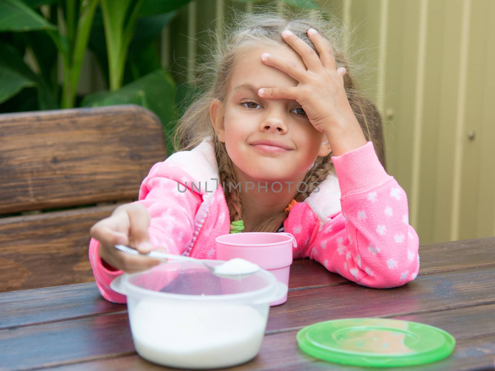 Girl sitting at a wooden table on the porch, and breakfast