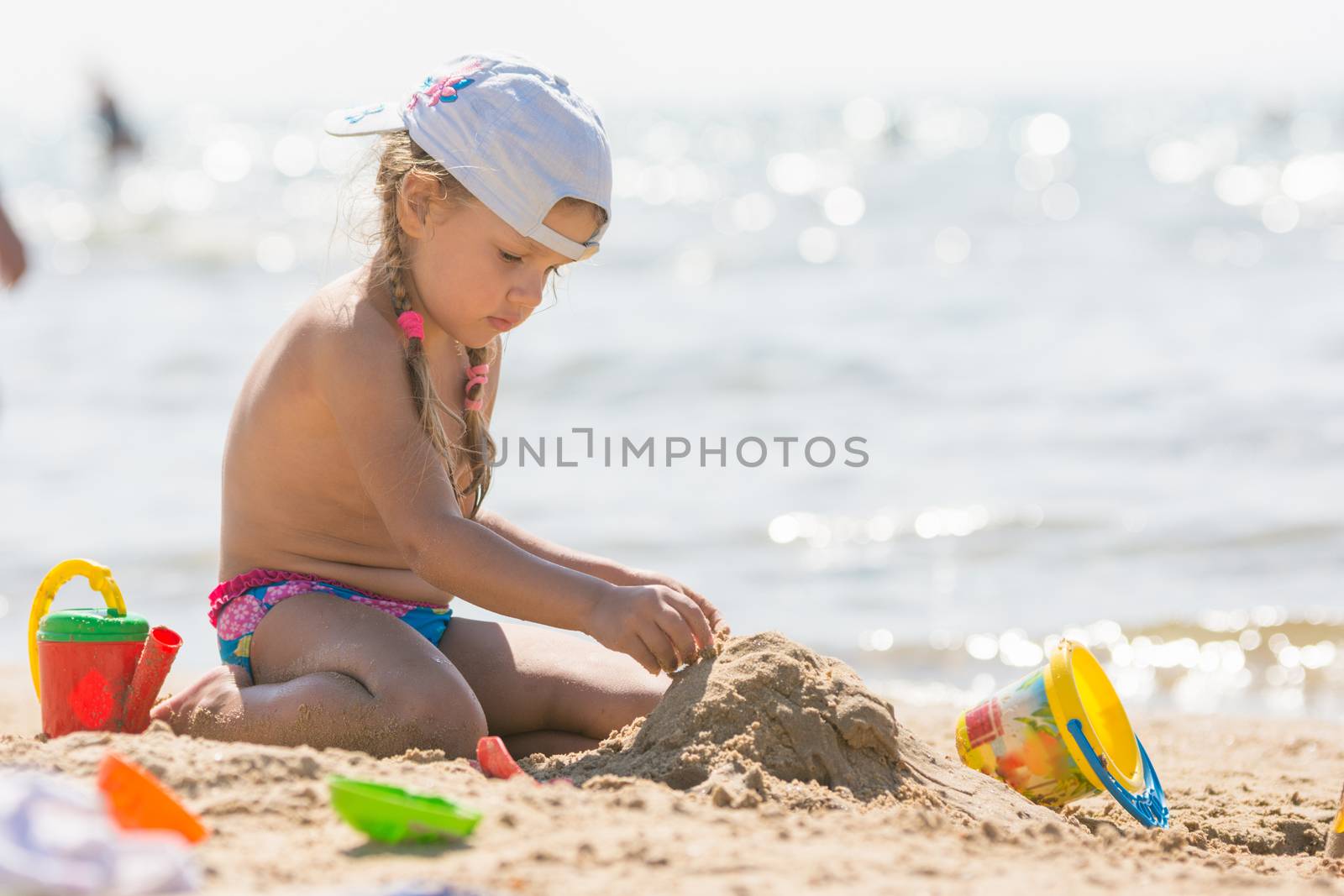 Four-year girl playing in the sand on the beach seaside