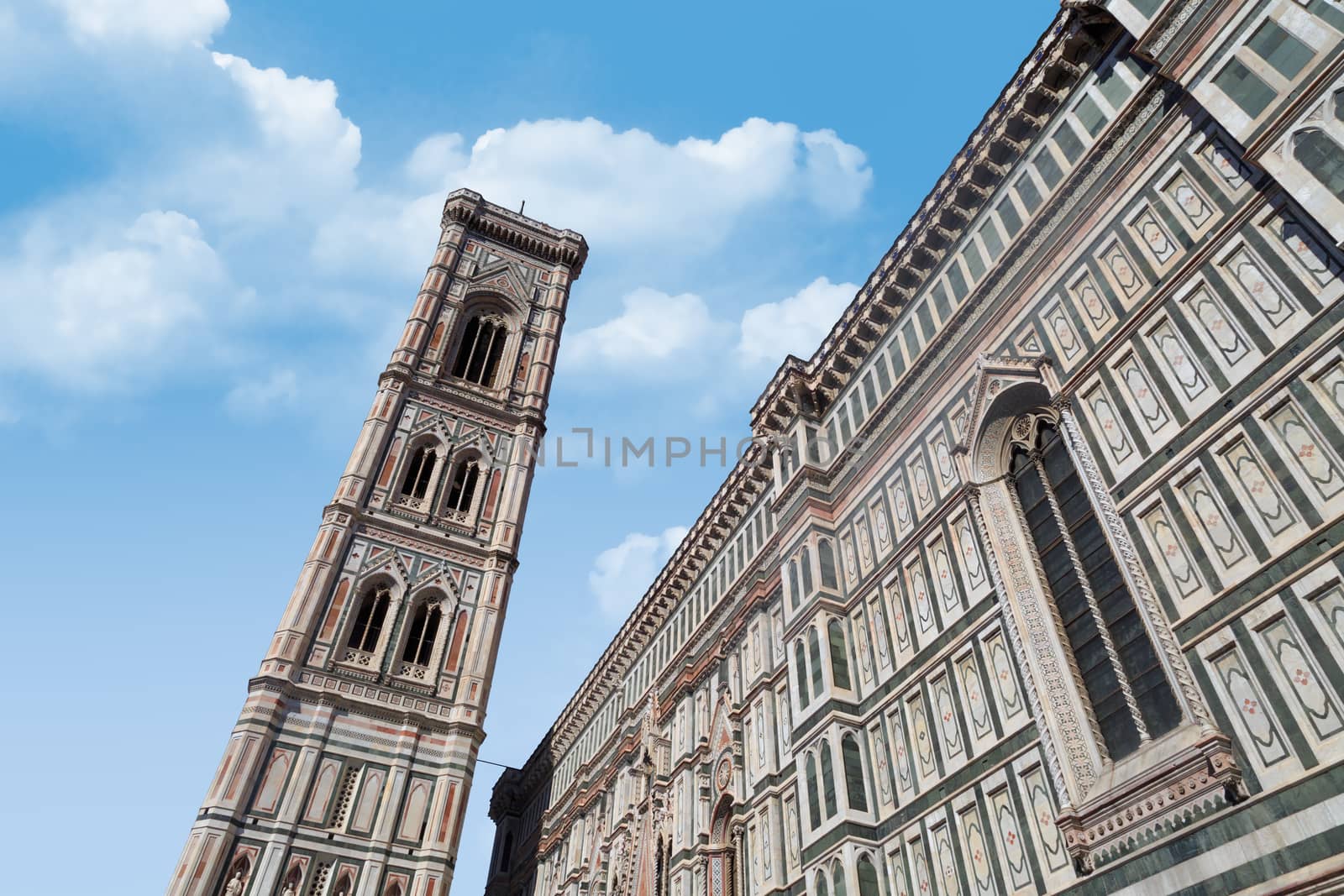 Bottom view of belfry tower of Florence Duomo, Santa Maria Del Fiore, on cloudy blue sky background.
