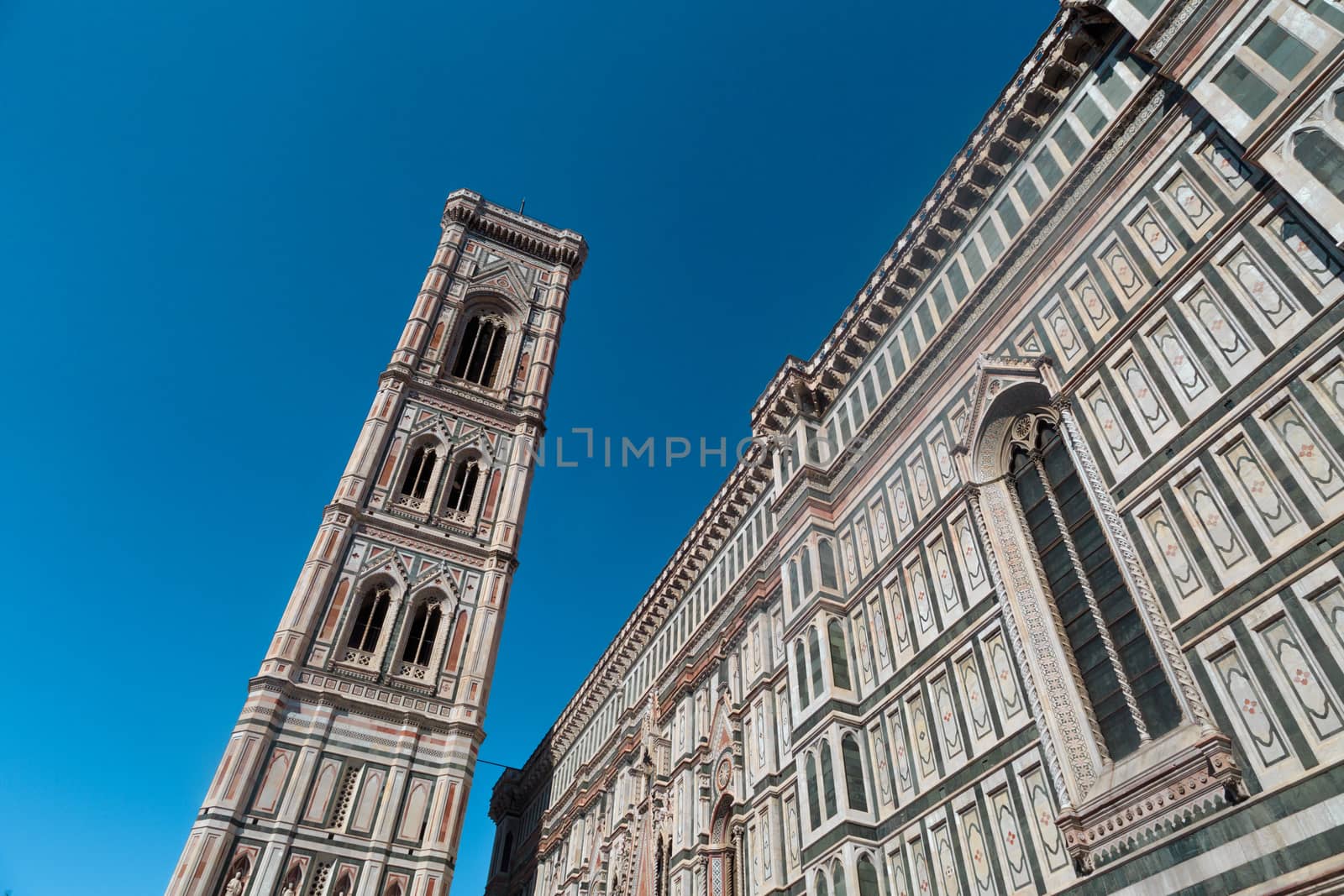 Bottom view of belfry tower of Florence Duomo, Santa Maria Del Fiore, on bright blue sky background.