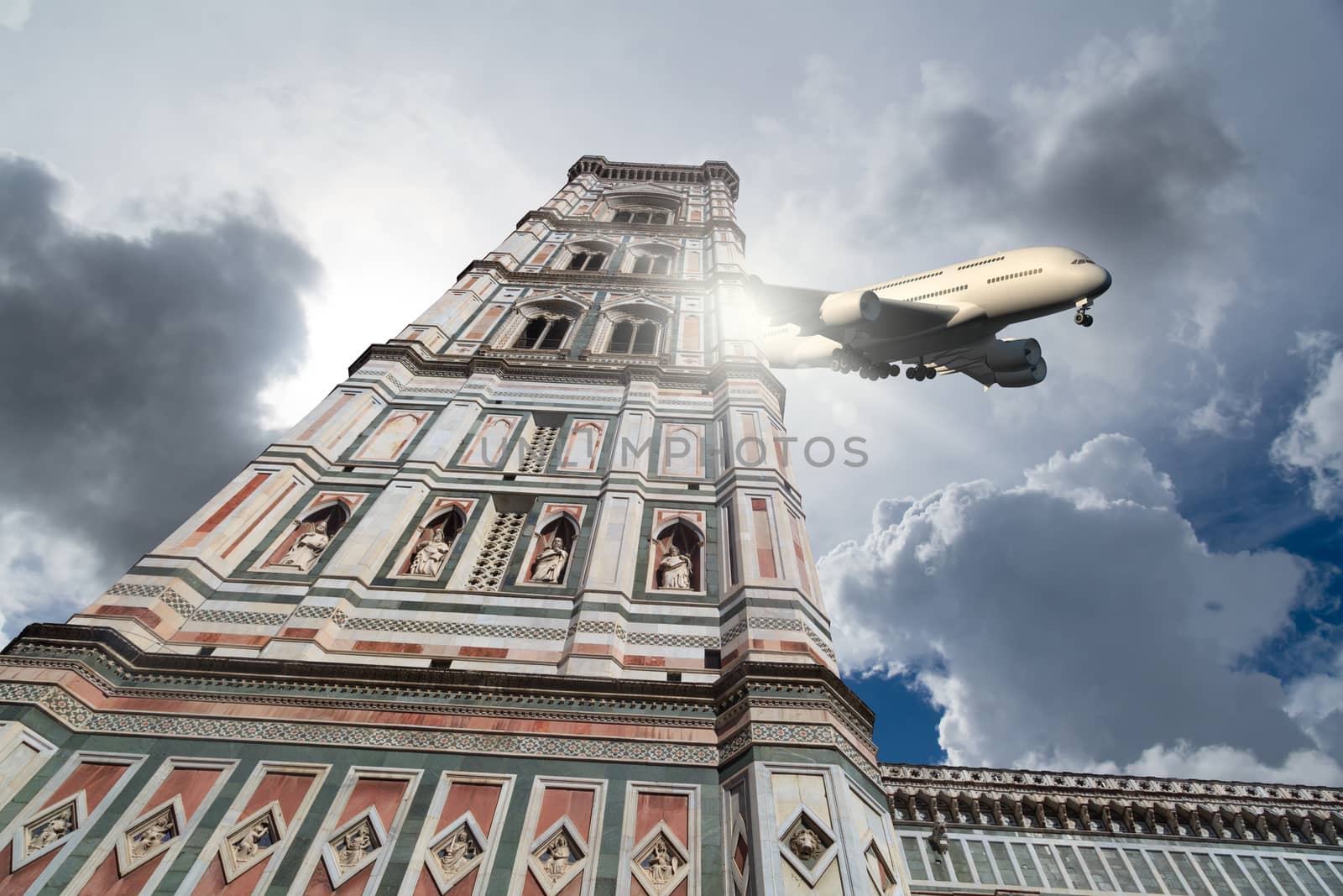 Bottom view of belfry tower of Florence Duomo, Santa Maria Del Fiore, on cloudy grey sky background with a plane.