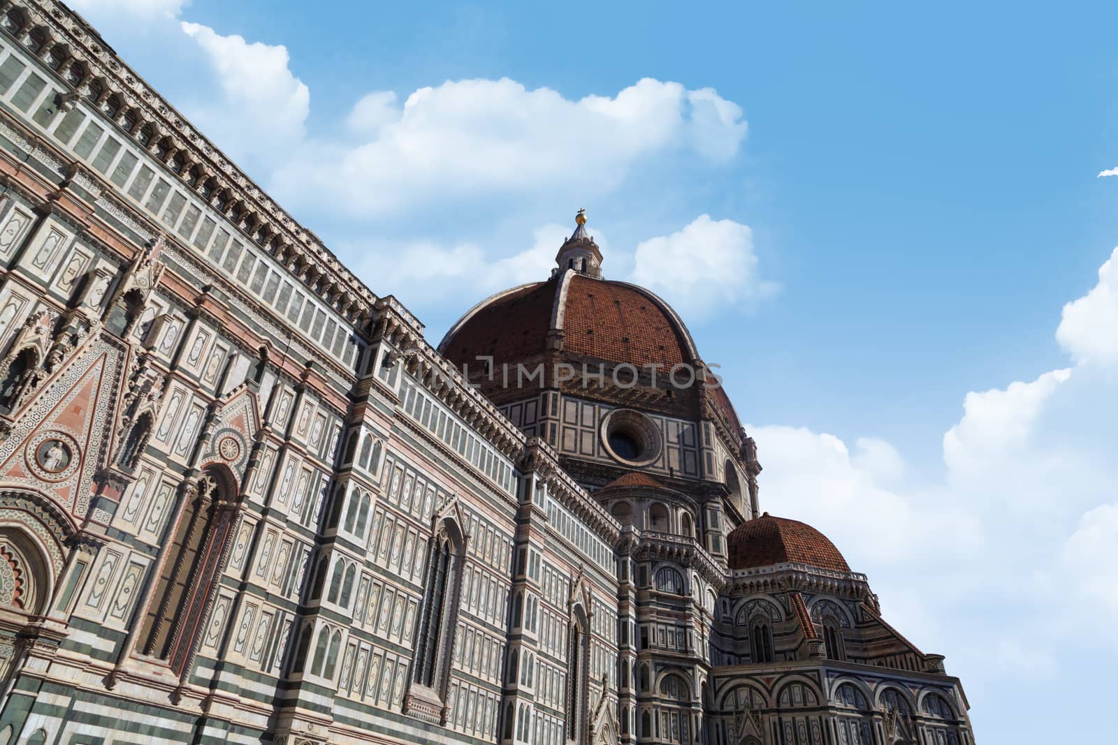 Side view of famous historical Florence Duomo, Santa Maria Del Fiore, on cloudy blue sky background.