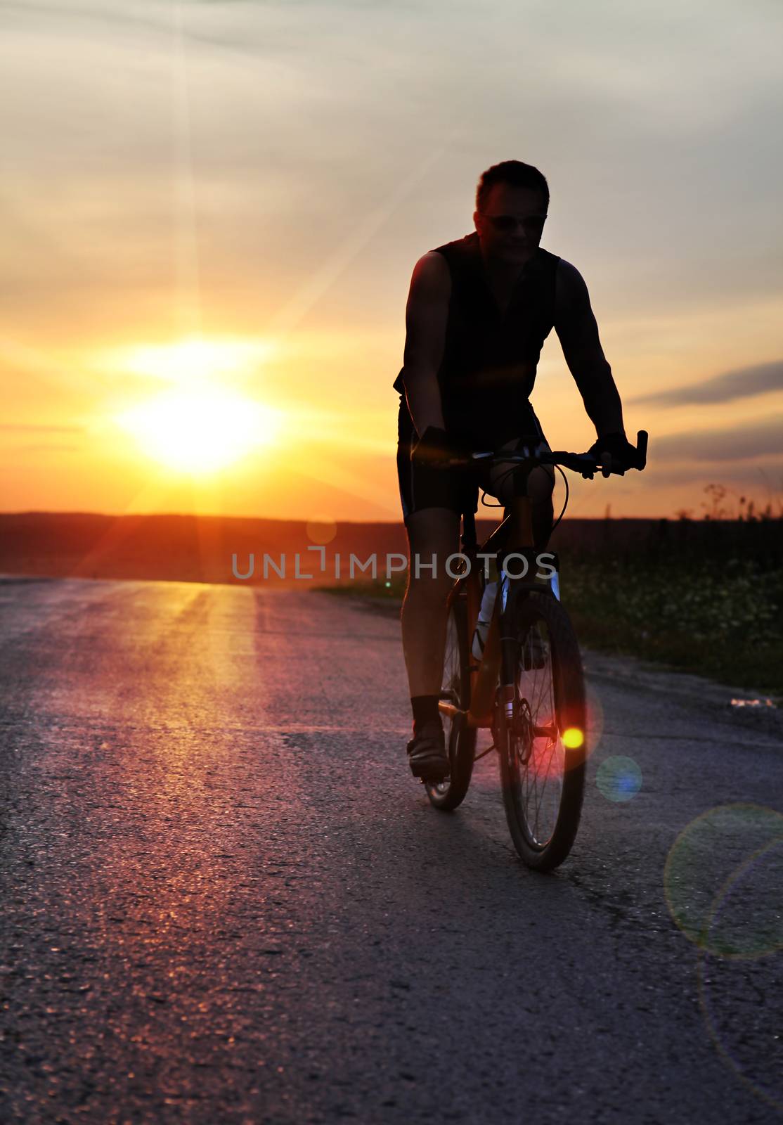 cyclist at sunset time by ssuaphoto