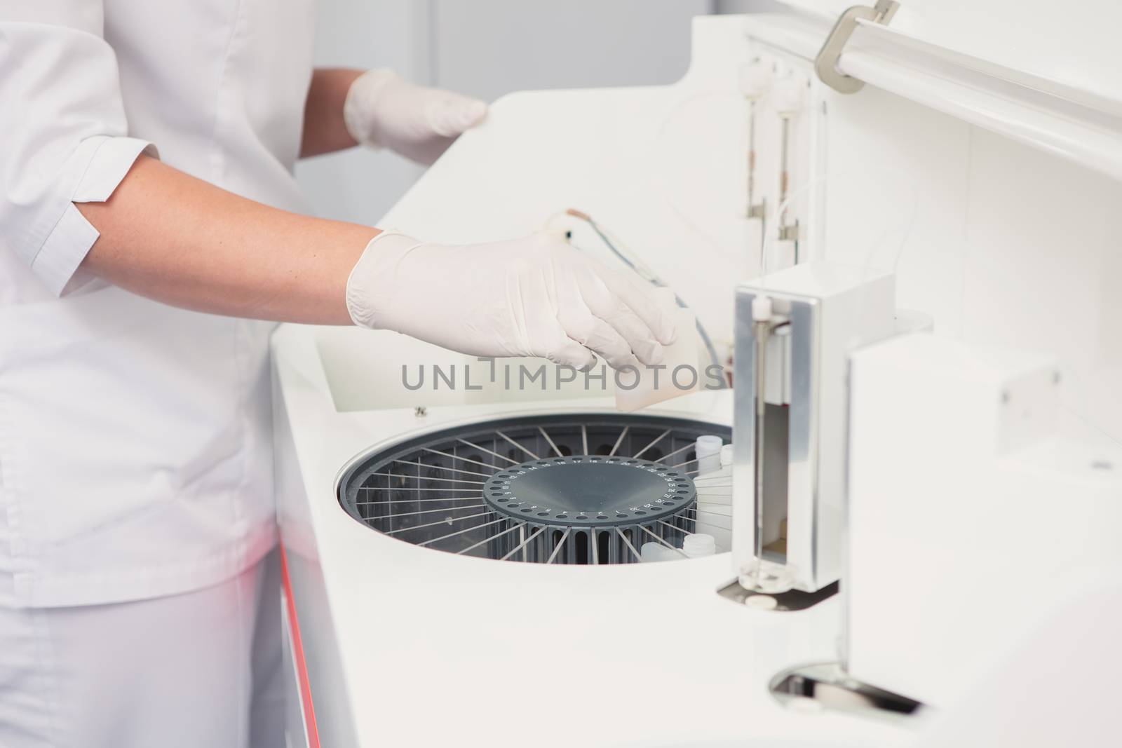 Lab tech loading samples into a chemistry analyzer by sarymsakov