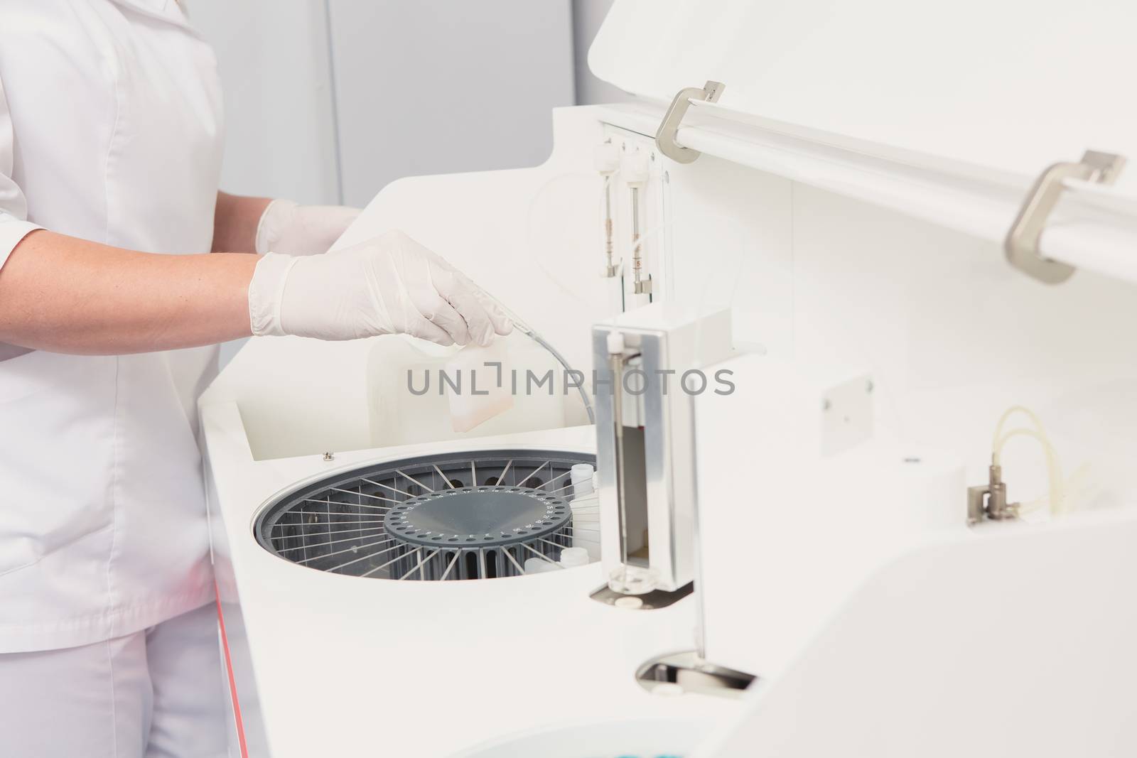 Lab tech loading samples into a chemistry analyzer by sarymsakov