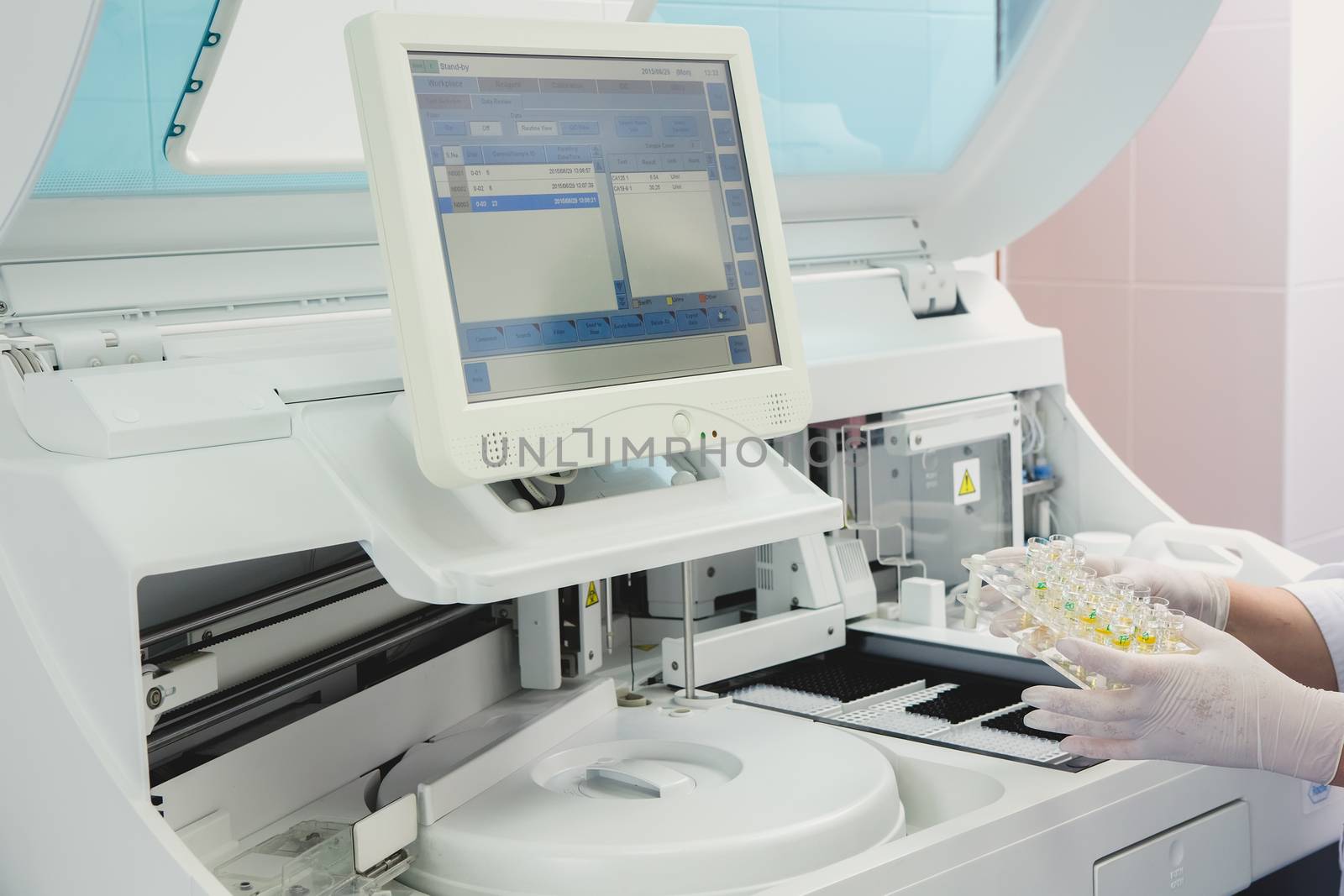 Lab tech loading samples into a chemistry analyzer by sarymsakov