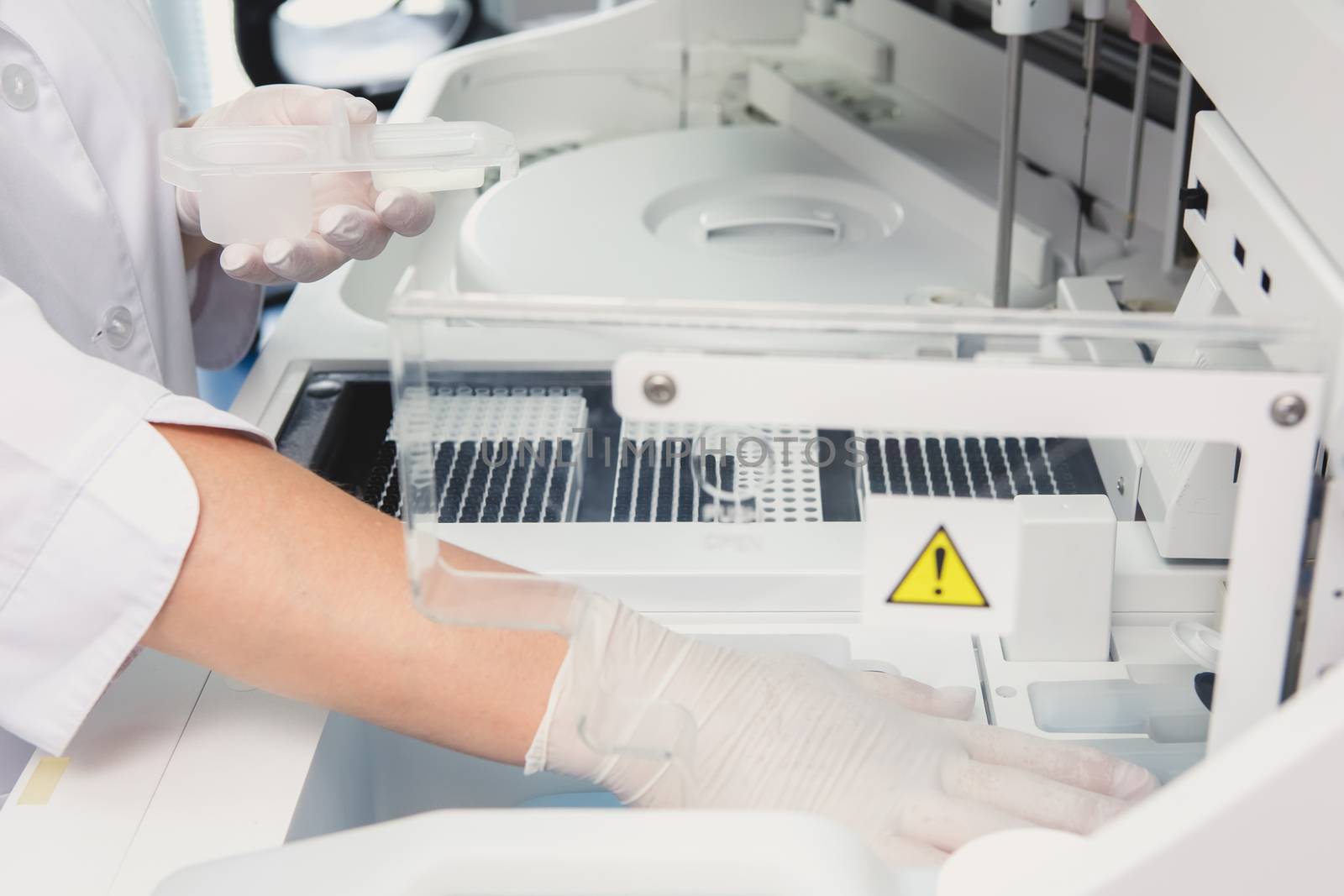 Lab tech loading samples into a chemistry analyzer by sarymsakov