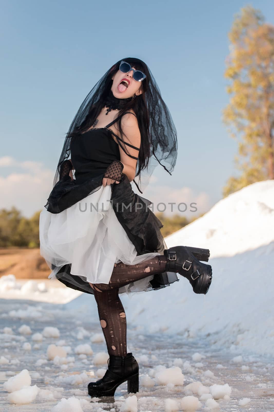 View of a beautiful young girl in gothic clothing on a salt evaporation pond.