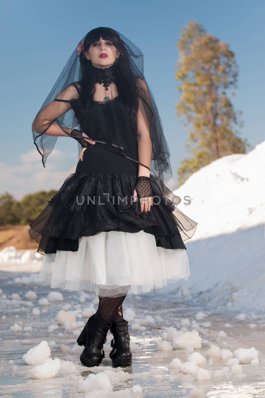 View of a beautiful young girl in gothic clothing on a salt evaporation pond.