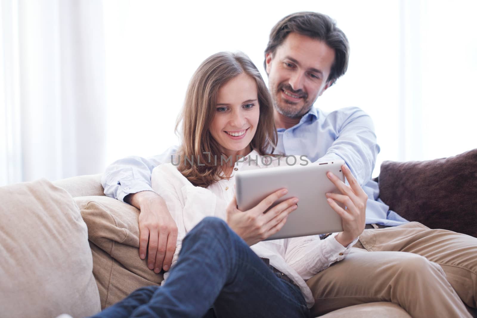 Cheerful couple using digital tablet at home