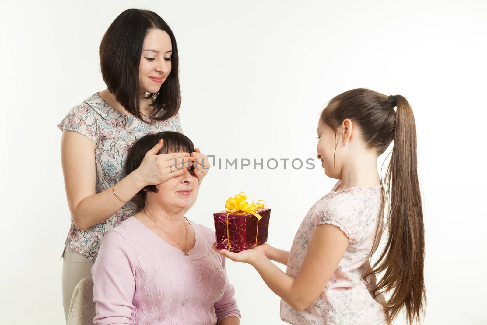 the daughter and the granddaughter give a gift to the grandmother