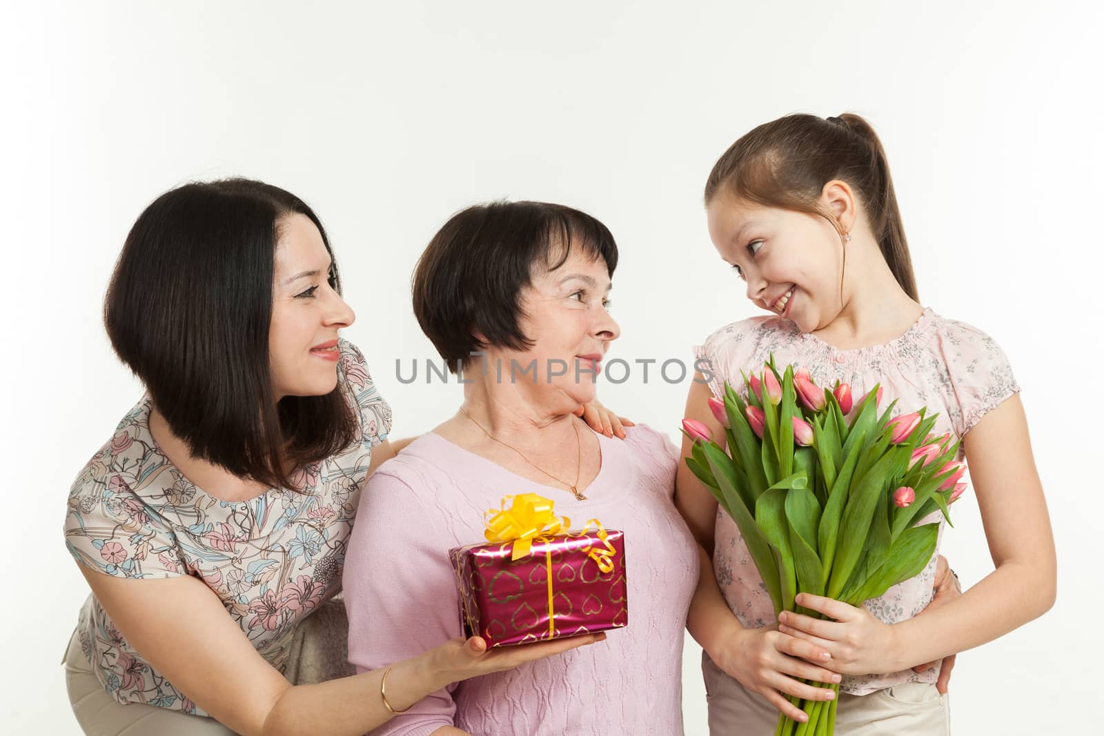 the daughter and the granddaughter give a bouquet of tulips to the grandmother