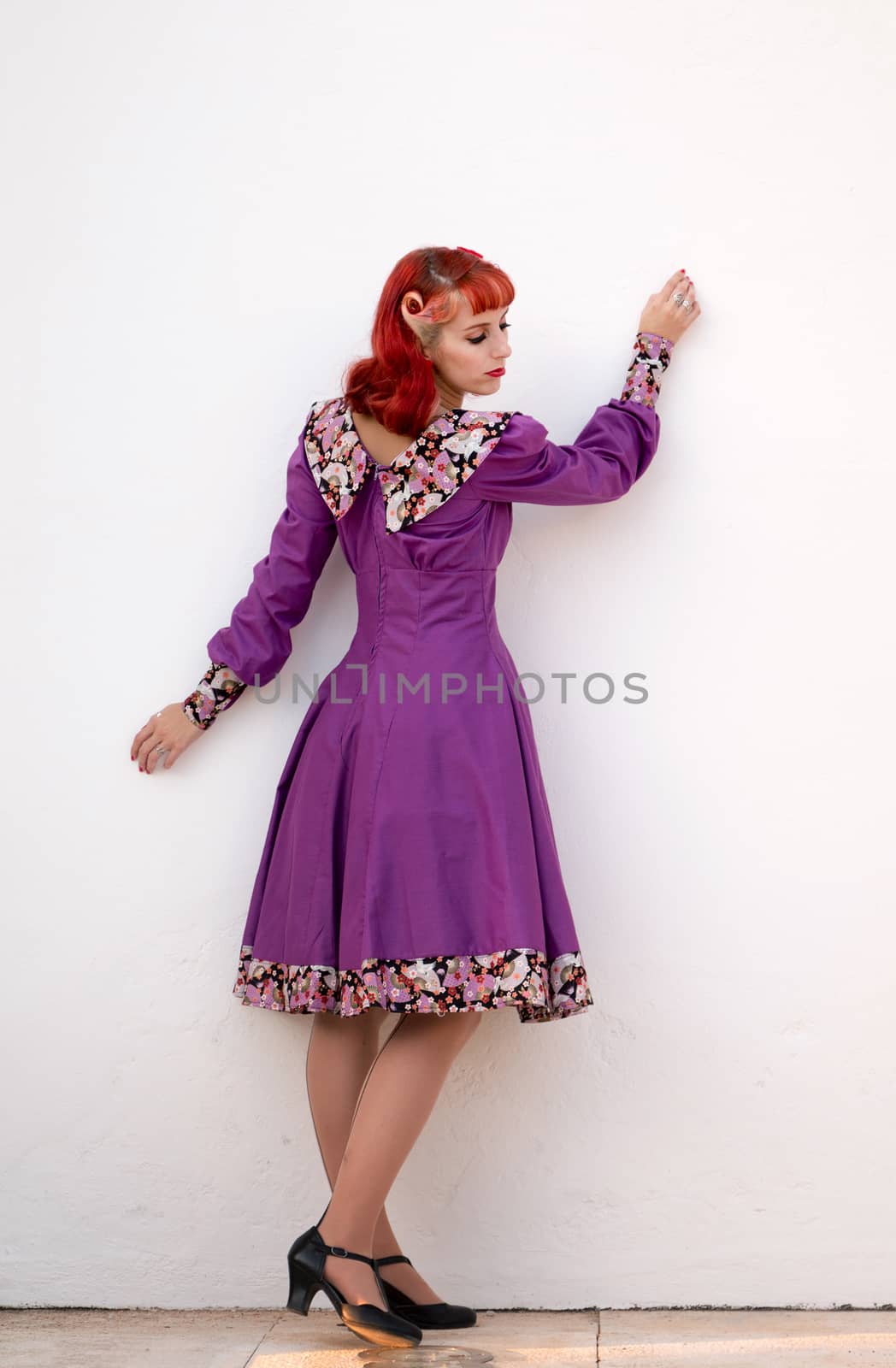 Close up view of a young redhead girl on a retro vintage dress on the urban city.