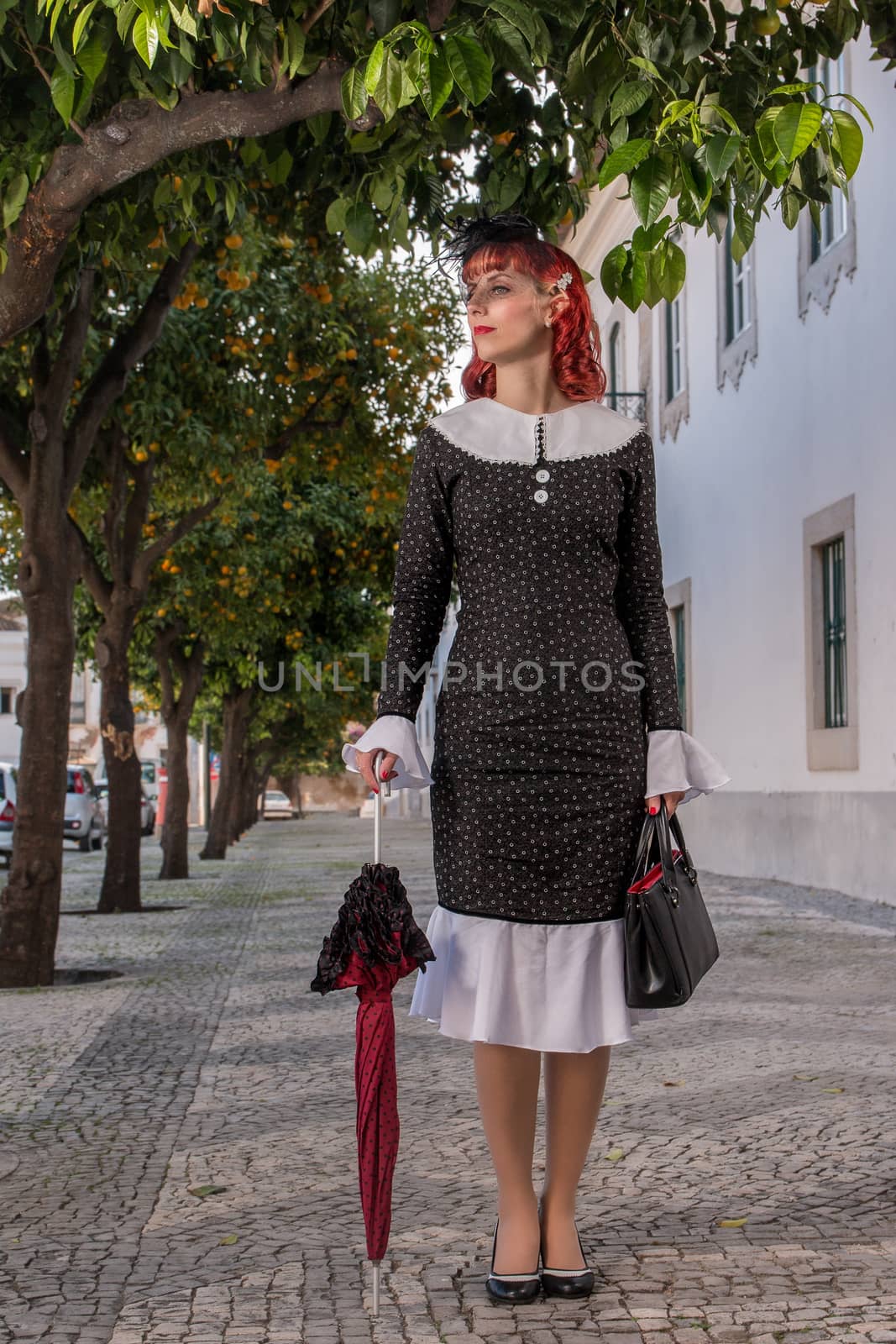 Close up view of a young redhead girl on a retro vintage dress on the urban city.