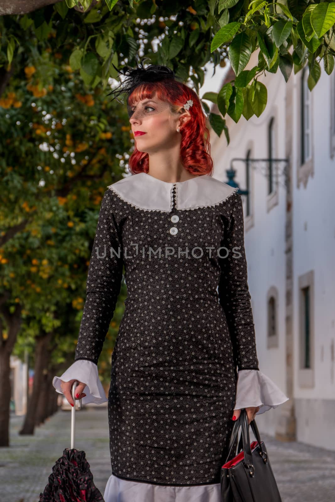 Close up view of a young redhead girl on a retro vintage dress on the urban city.