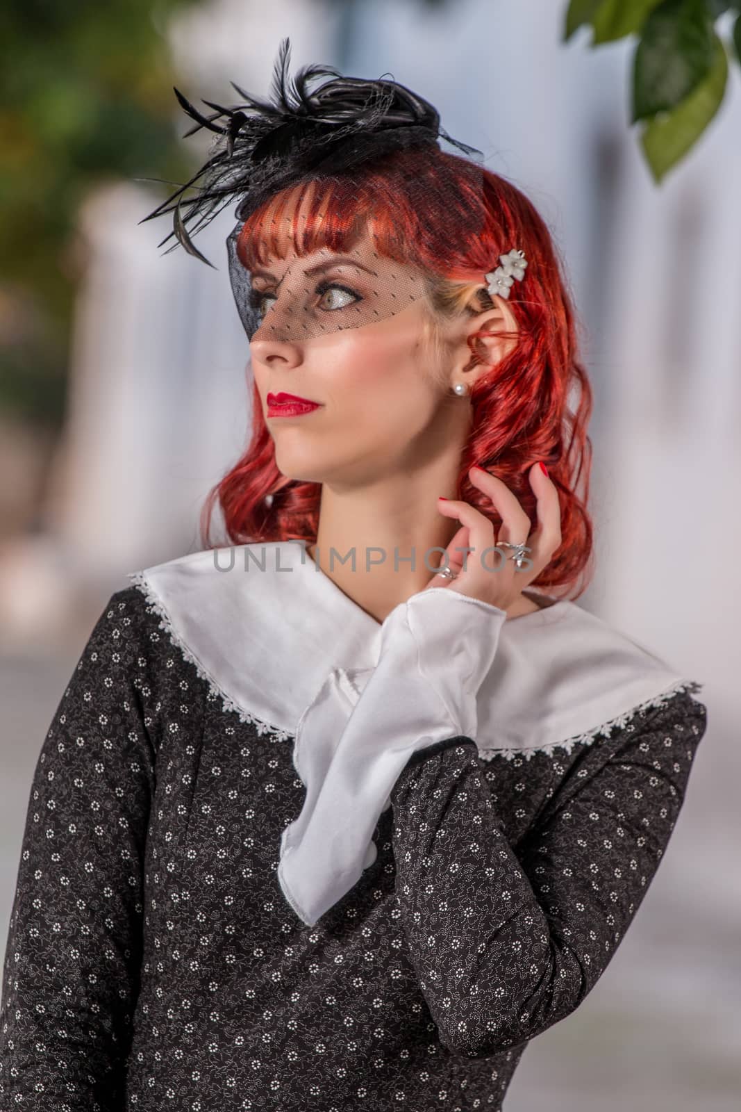 Close up view of a young redhead girl on a retro vintage dress on the urban city.