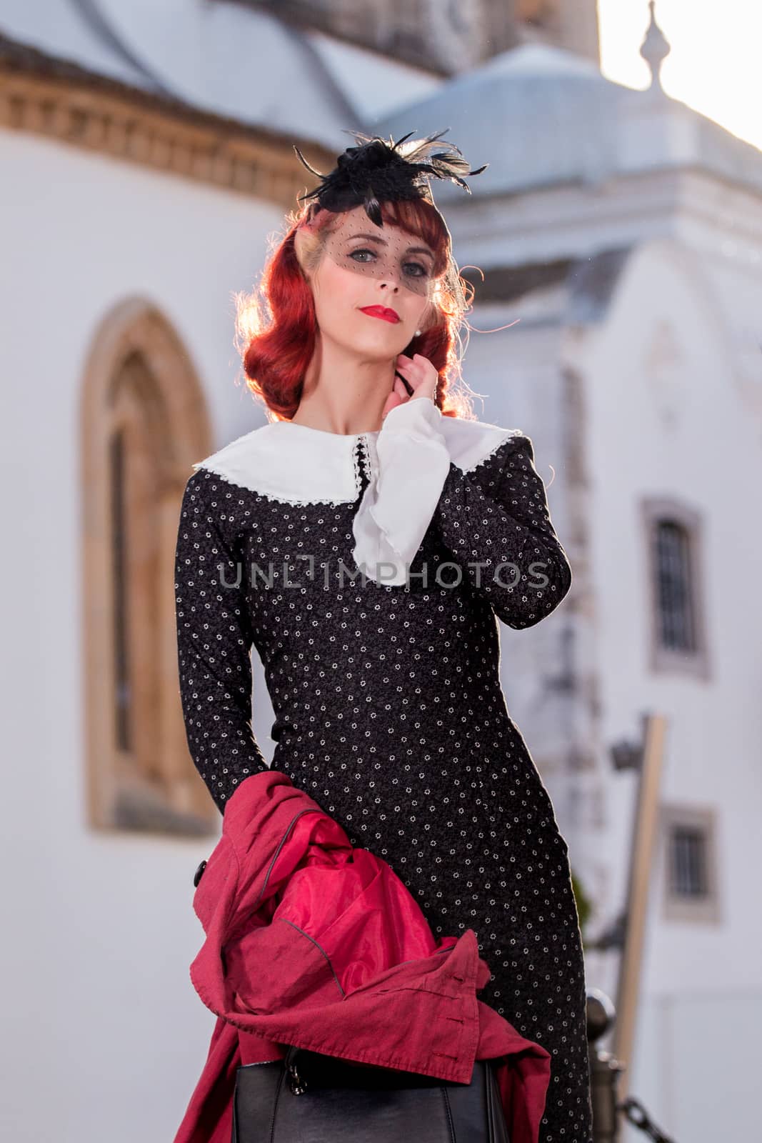 Close up view of a young redhead girl on a retro vintage dress on the urban city.