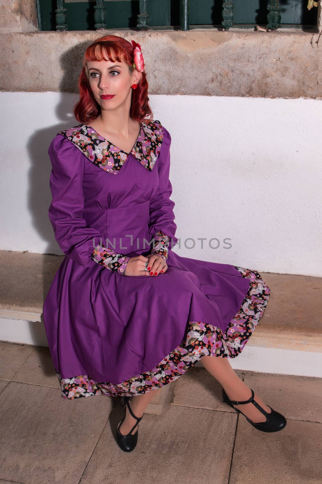 Close up view of a young redhead girl on a retro vintage dress on the urban city.