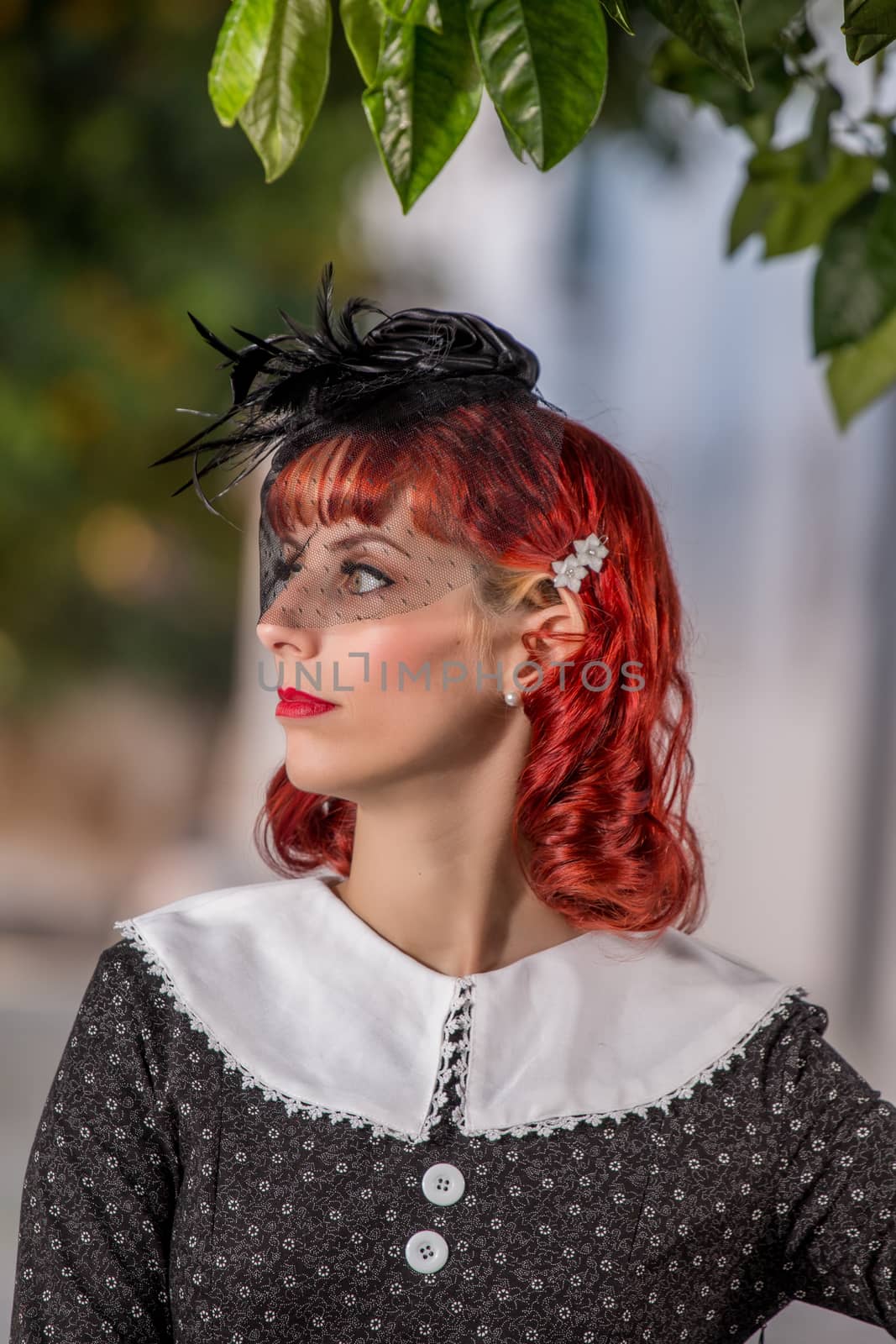 Close up view of a young redhead girl on a retro vintage dress on the urban city.