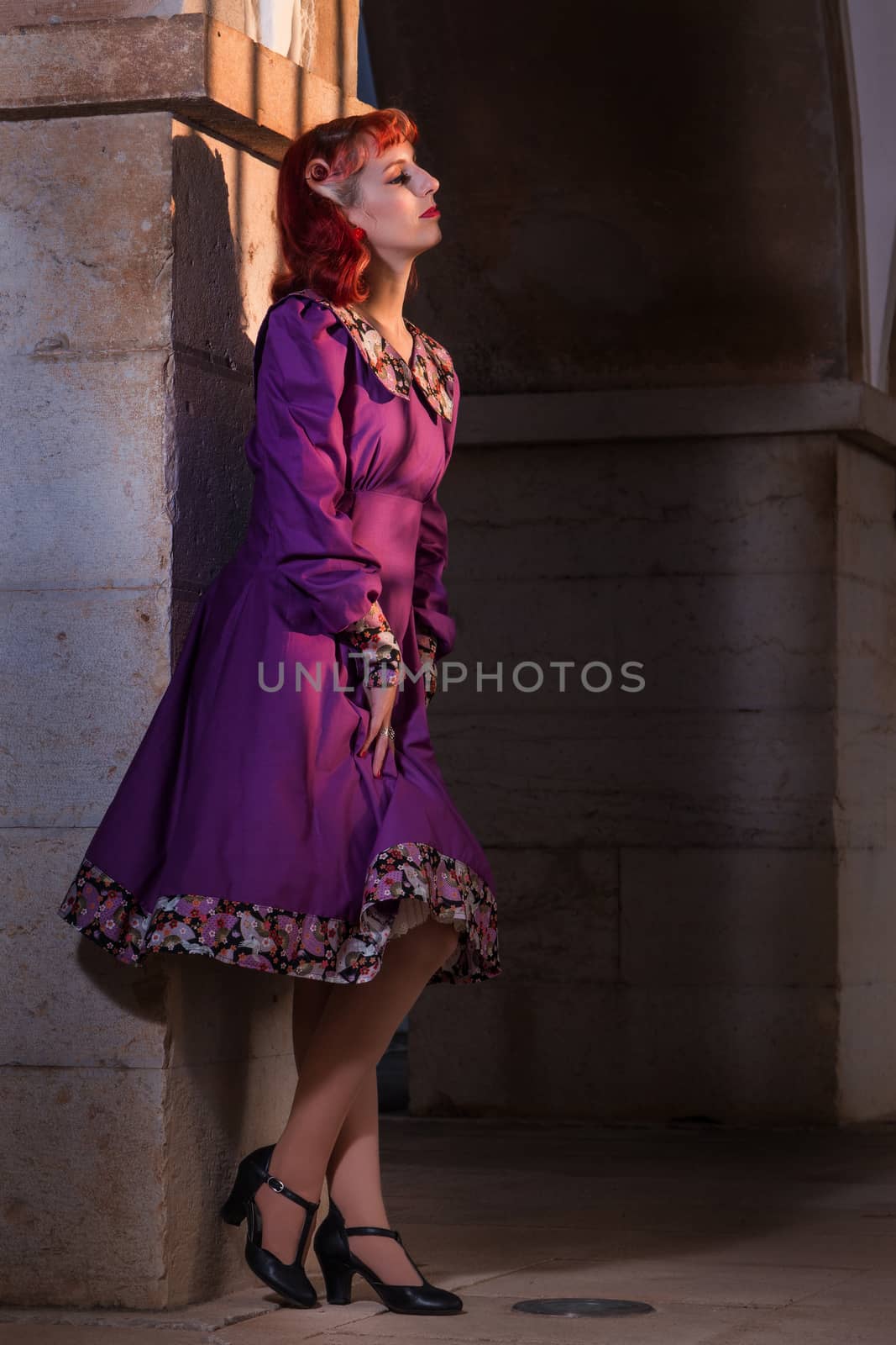 Close up view of a young redhead girl on a retro vintage dress on the urban city.