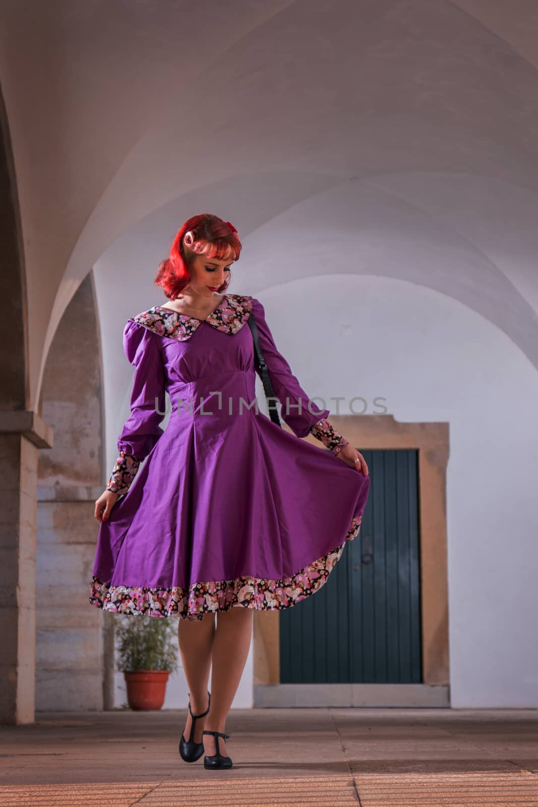 Close up view of a young redhead girl on a retro vintage dress on the urban city.