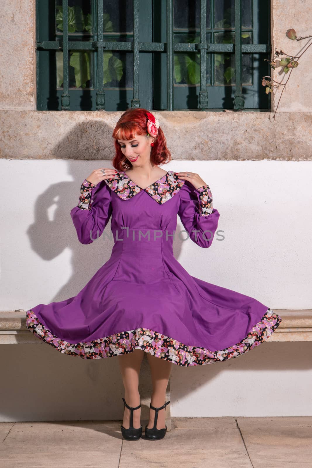 Close up view of a young redhead girl on a retro vintage dress on the urban city.