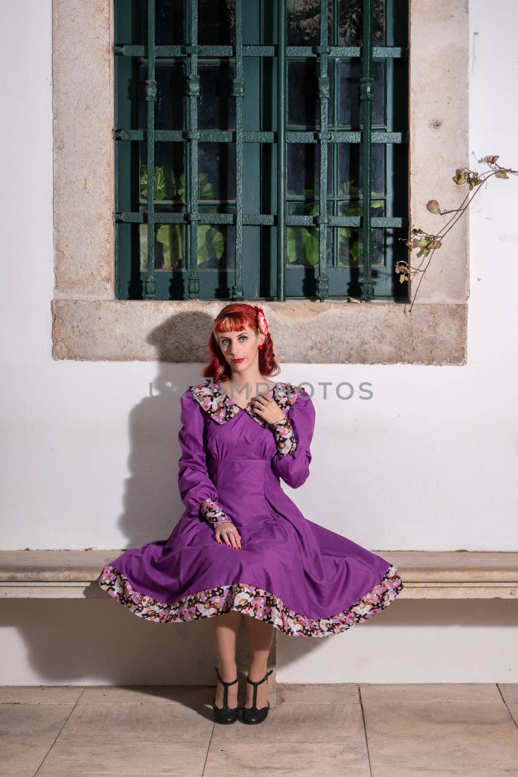 Close up view of a young redhead girl on a retro vintage dress on the urban city.